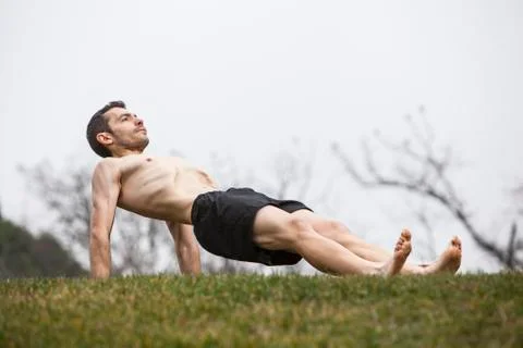 Man performing abdominal exercise lying on the grass Stock Photos