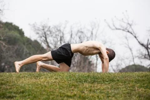 Man performing abdominal exercise lying on his stomach in the grass Stock Photos