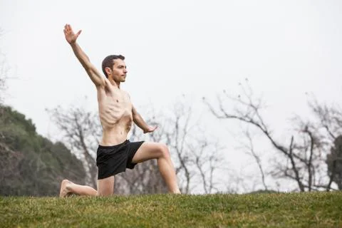 Man performing abdominal exercise with one knee on the grass Stock Photos
