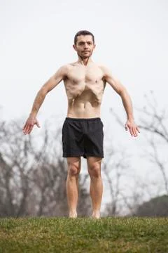 Man performing abdominal exercise standing on the grass Stock Photos