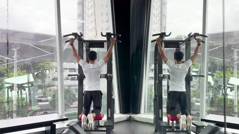 Man Performing Assisted Pull-Ups in Modern Gym With City View Stock Footage 326849284