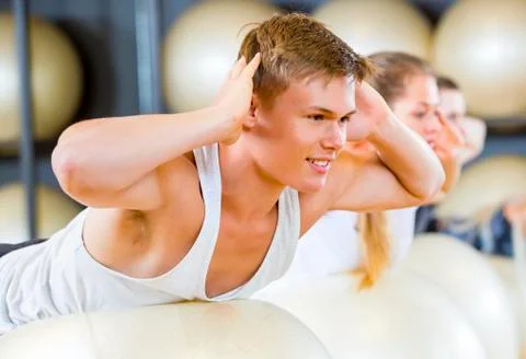 Man Performing Back Extension Exercise With Friends Stock Photos