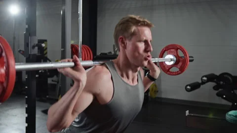Man Performing Barbell Squats during Intense Strength Training Workout Stock-Footage 339889232