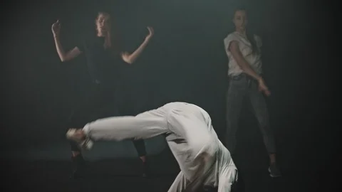 A man performing breakdancing tricks - two women dancing on the background Stock Footage 124127108