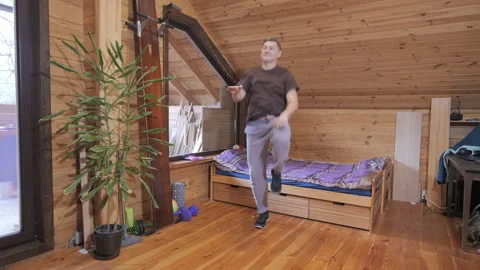 Man performing cardio exercise indoors in wooden attic interior Stock Footage 335444867