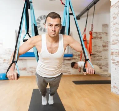 Man performing chest press with TRX straps during Pilates training Stock Photos