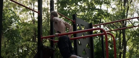 Man performing dips on parallel bars in outdoor fitness park Video stock 323934229