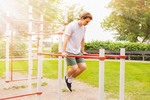 Man performing dips on parallel bars at an outdoor sports ground. Calisthen.. Stock Photos