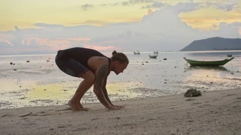 Man performing handstand on beach during sunset 스톡 동영상 74772613