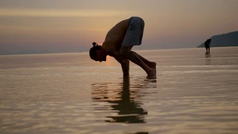 Man performing handstand in the sea at sunset Stock Footage 74769831