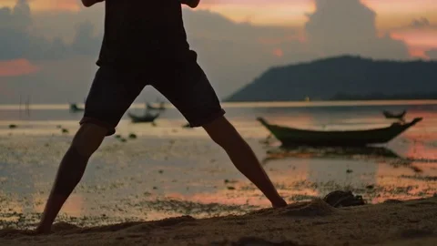 Man performing headstand on the beach during sunset Stock Footage 74905382