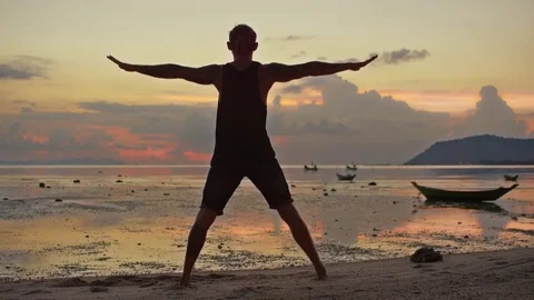 Man performing a headstand at the coast during sunset Stock Footage 74769086