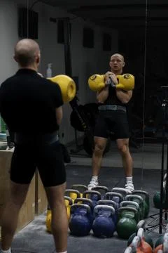 Man performing kettlebell clean exercise in gym, strength training Stock Photos