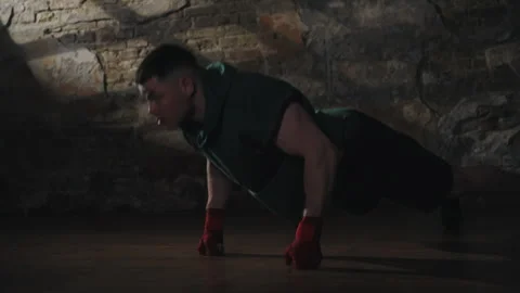Man performing knuckle push-ups in dimly lit gym Stock Footage 299942355