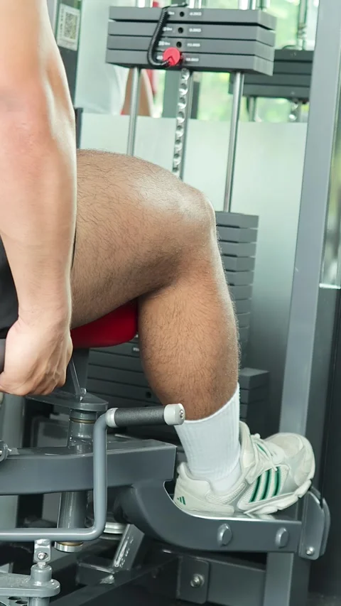 Man Performing Leg Extension Exercise on Gym Machine Stock Footage 314040174