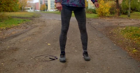 Man performing lunges and squats on dirt path in autumn park near city Stock Footage 348648145