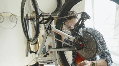 Man is performing maintenance on his mountain bike. Stock Footage 305642363