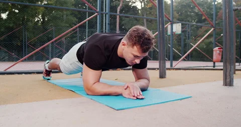 A man is performing a plank exercise outdoors, enhancing his overall fitness and Stock Footage 317979501