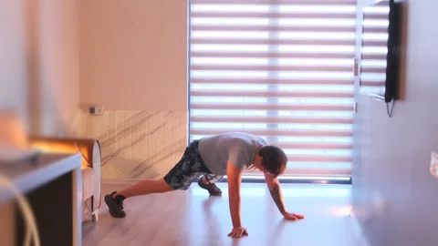 Man performing plank jacks at home, dynamic cardio core workout improving Stock Footage 333617758