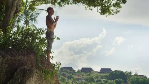 Man performing prayer pose on the rock Stock Footage 74772685