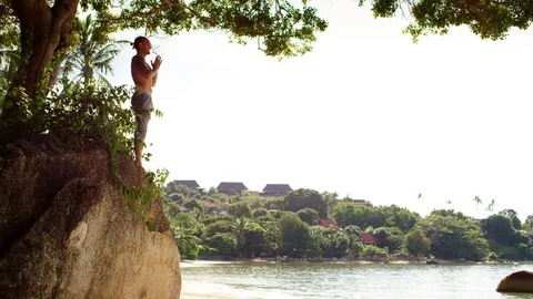 Man performing prayer pose on the rock Stock Footage 74775229