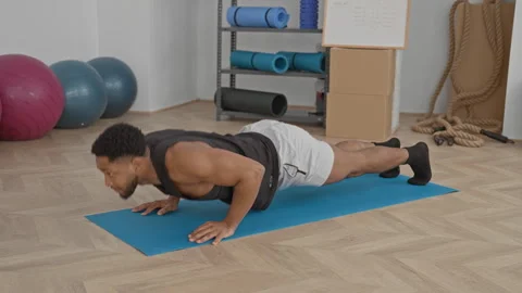 Man performing pushups on blue mat in studio amid exercise balls, ropes and.. Stock Footage 337440303
