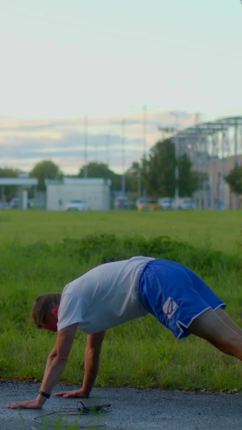 A man performing pushups outdoors while dressed in athletic gear apparel Видео 317340752