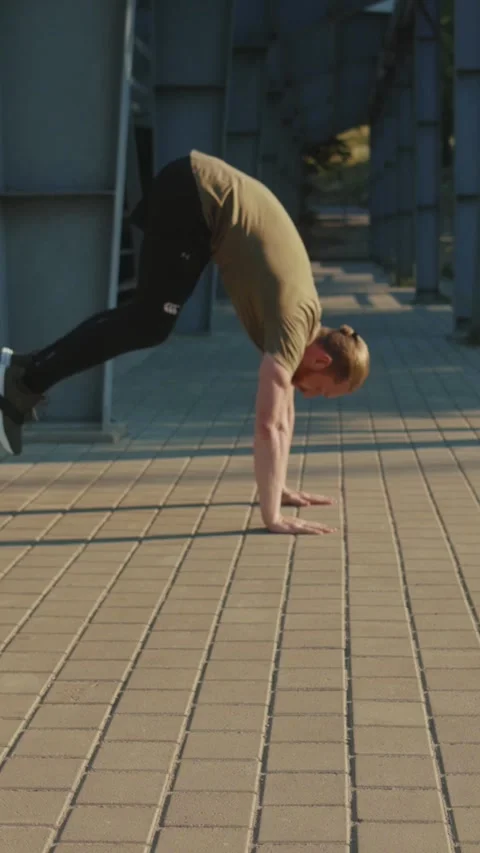 A man performing pushups in an urban environment, showcasing his physical Stock Footage 305878354