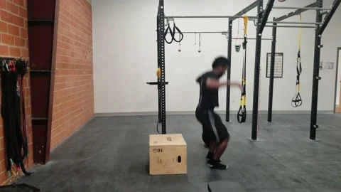 Man Performing Single Leg Box Jump Exercise in Crossfit Gym Stock Footage 146554499