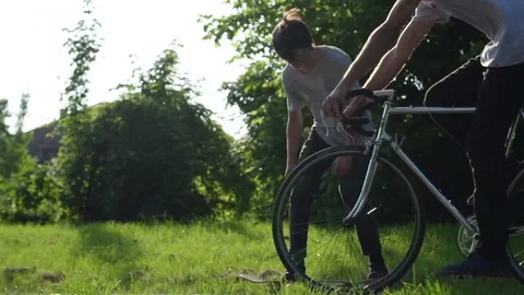 Man performing skating trick besides moving cycle in park Stock Footage 71558253
