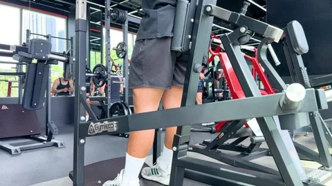 Man Performing Squats on Smith Machine in Modern Gym Stock Footage 320442550
