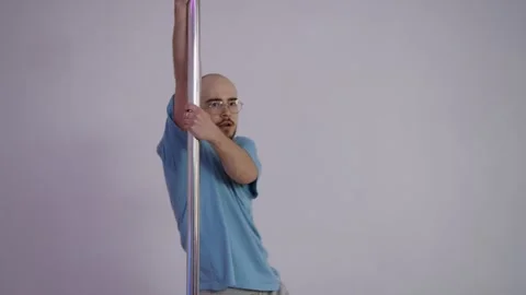 A man is performing a striptease dance, spinning on a pole against an abstract Stock Footage 305093193