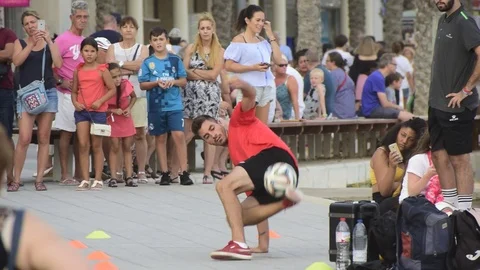 Man performing tricks with a ball on the street while a crowd watches the show. Stock Footage 113671709
