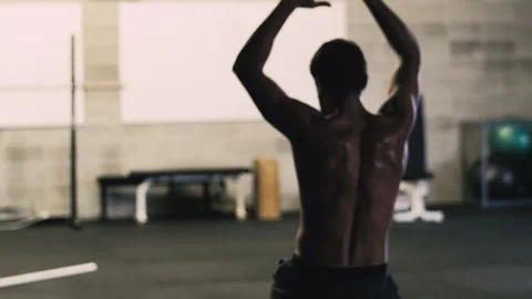 Man performing upper body stretch on one knee in gym fitness session Stock Footage 312760702