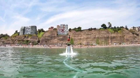 Man performing water jetpack flight by coastal city Stock Photos