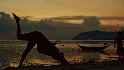 Man performing yoga on beach during sunset Stock Footage 74773211