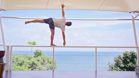 Man performing yoga on railing against sea Stock Footage 74773344