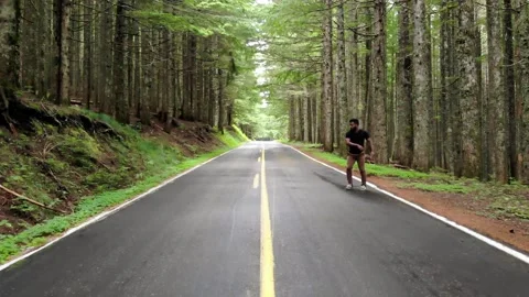 Man Performs Acrobatic Stunt on Paved Road in Forest in Slow Motion Stock Footage 142341184