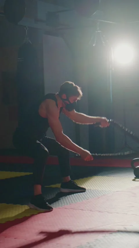 Man performs battle rope exercise under studio lighting Stock-Footage 335506240