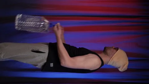 Man performs Bicep curls using large bottles of water as a weight.Vertical. Stock Footage 136239039