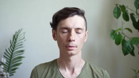 A man performs breathing practice sitting in a calm environment in a room Stock Footage 277876382