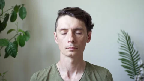 A man performs breathing practice sitting in a calm environment in a room Stock Footage 277876406