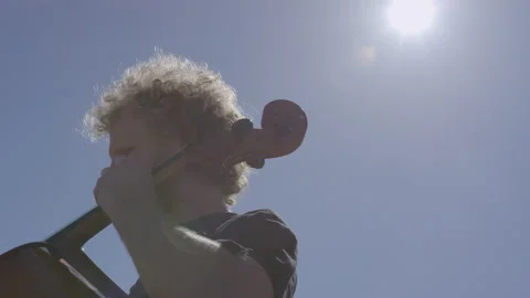Man performs cello solo outdoors under bright sunny sky Stock Footage 312630537