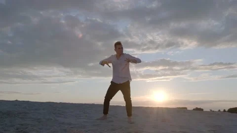 Man performs contemporary choreography on the sand at sunset. Slow motion Stock Footage 135611324