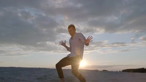 Man performs contemporary choreography on the sand at sunset. Slow motion Stock Footage 135611331