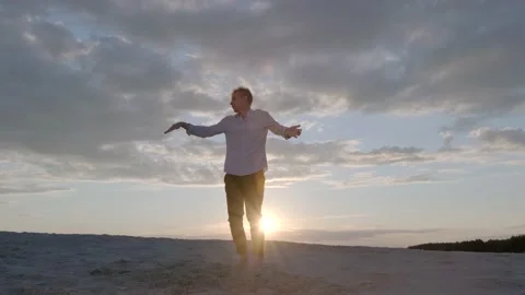 Man performs contemporary choreography on the sand at sunset. Slow motion Stock Footage 135611345