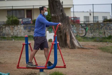 Man performs elliptical exercises on machines in public square. use of mask i Stock Photos