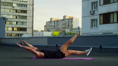 A man performs an exercise on the press by raising his arms and legs alternately Stock Footage 250021059