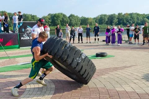 Man performs Exercise Tire Turning during strength competition Stock Photos