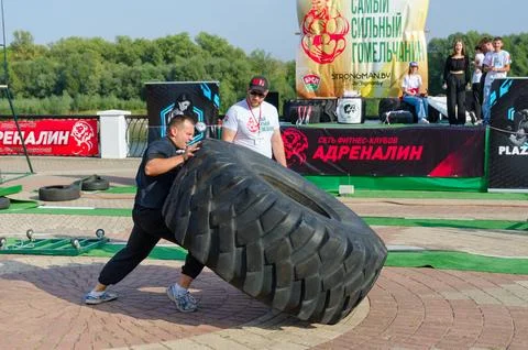 Man performs Exercise Tire Turning during strength competition Stock-Fotos